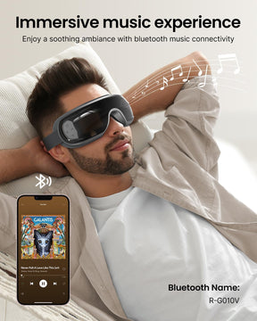 A man reclines on a couch wearing a Renpho Eyeris 3 Eye Massager equipped with an eye care feature, enjoying music through a smartphone displaying an album cover. (A)