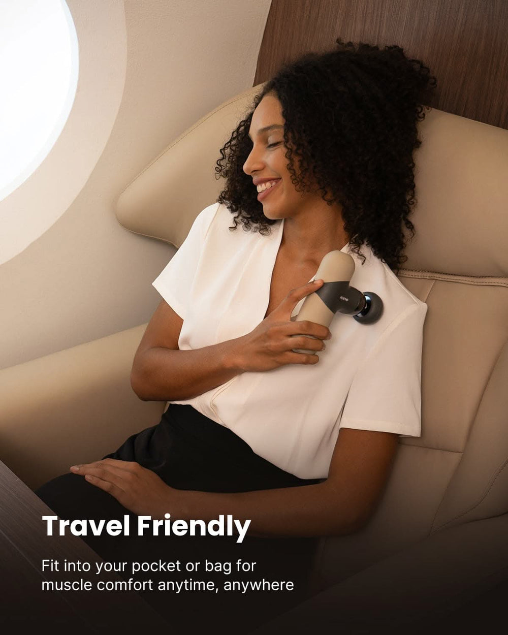 A woman with curly hair wearing a white blouse and black pants relaxes in an airplane seat, using the RENPHO US Mini Thermal Massage Gun on her shoulder. The background shows the interior of an airplane. Text at the bottom reads: "Travel Friendly - Fits into your pocket or bag for muscle comfort anytime, anywhere.