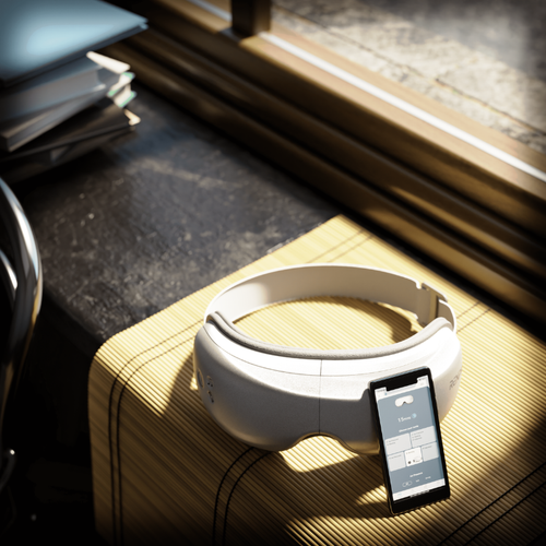 A Renpho Eyeris Smart Eye Massager is sitting on a table next to a personalized headset.