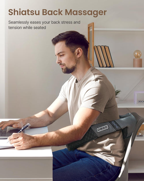 A man sits at a desk using a computer, wearing a Renpho U-Neck 2 Neck & Shoulders Massager over his chair. The environment is calm with soft lighting and minimalistic decor. The massager, featuring