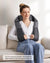 A woman relaxes on a white sofa, using a gray Renpho U-Neck 2 Neck & Shoulders Massager. She wears a white v-neck sweater and blue jeans, eyes closed, with a serene expression. Text advises not to lean
